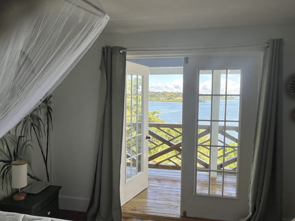 Bedroom doors open onto a balcony with a view over the bay